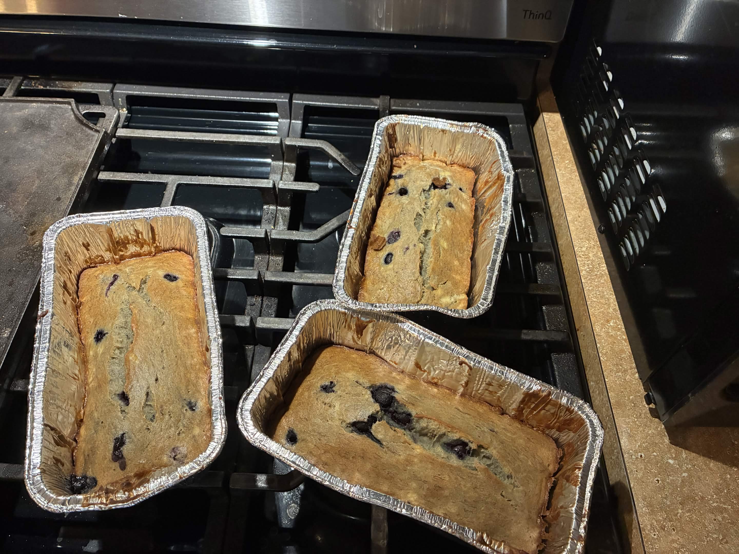 Three blueberry banana bread loaves cooling on the stovetop.